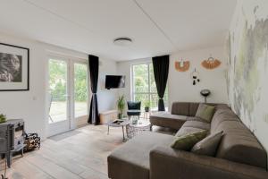 sala de estar con sofá y TV en Het Huys Ewijk mooi luxe en een laadpaal, en Ewijk