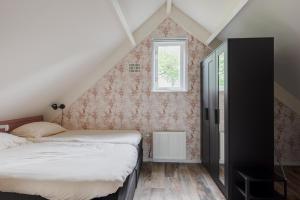 1 dormitorio en el ático con 2 camas y ventana en Het Huys Ewijk mooi luxe en een laadpaal, en Ewijk
