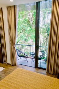 een kamer met een balkon en een glazen schuifdeur bij Boom Casa Homestay in Hue
