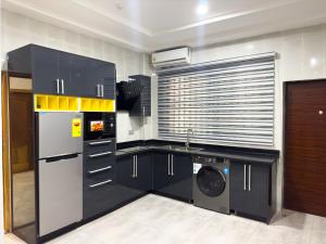a kitchen with black cabinets and a washer and dryer at The AUD Luxury Apartments in Kumasi