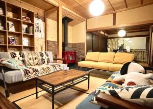 Sala de estar con 2 sofás y mesa de centro en ゲストハウスでたらめ荘, en Yamakami