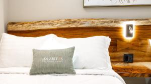 a bed with white pillows and a wooden headboard at Hotel Boutique Los Abetos in Boquete