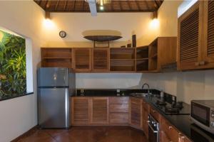 a kitchen with wooden cabinets and a stainless steel refrigerator at Sunset Beach Villa Zanzibar 