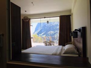 a bedroom with a bed with a view of a mountain at Mandara Mount Hotel in Ella