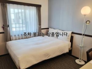 a hotel room with a bed and a window at Toyoko Inn Busan Haeundae 2 in Busan