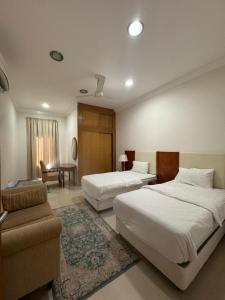 um quarto de hotel com duas camas e um sofá em بيت السلطانة للأجنحة الفندقية em Salalah