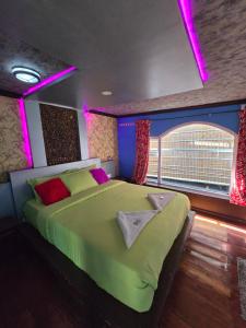 una camera da letto con un grande letto verde con luci viola di Beach Paradise Day Cruise Houseboat - VACCINATED STAFF a Alleppey