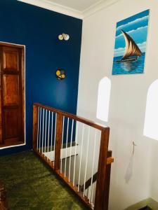 Seafarers Loft في Stone Town: غرفة بها درج بجدار ازرق ولوحة قارب شراعي