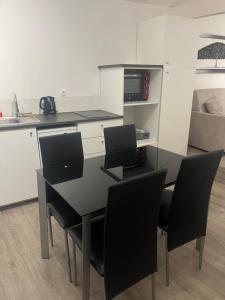 una mesa de comedor negra con sillas y una cocina en Studio 80, en Bourg-en-Bresse