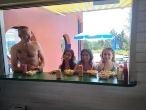 un hombre y tres niños sentados en una mesa con comida en Camping Hurongues, en Pomeys