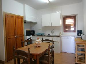 eine Küche mit einem Holztisch und eine Küche mit weißen Schränken in der Unterkunft Apartamento Vilamaniscle, 3 dormitorios, 6 personas - ES-228-169 in Vilamaniscle