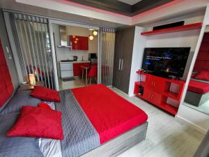 a bedroom with a large bed with red pillows and a television at Cozy Apartment with Lagoon View in Manila