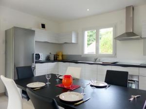 cocina con mesa negra y sillas en una habitación en Gîte Saint-Rémy-en-Rollat, 3 pièces, 4 personnes - FR-1-489-492, en Saint-Rémy-en-Rollat