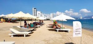 Grand Gosia Hotel في نها ترانغ: مجموعة من الناس جالسين على شاطئ فيه مظلات
