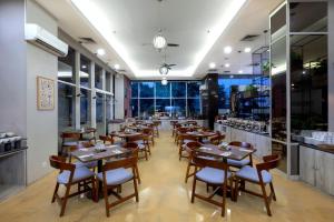 un ristorante con tavoli e sedie in legno e finestre di Quest Hotel Darmo - Surabaya by ASTON a Surabaya
