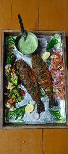 a tray of food with fish and vegetables and a dip at Dhauladhar Woodhouse in Malotha