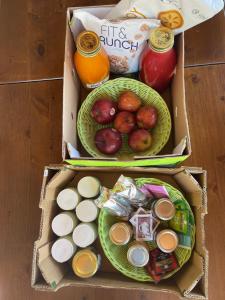 two boxes filled with food and fruit on a table at La FIOCCHINA - Magic Place - apartments & studios in Garda Lake - countryside farmhouse, inside the middle of the lake in Salò