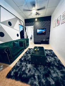 a living room with a green couch and a black rug at Kuu Inn Homestay Tmn Sri Wang Fasa 2 in Arau