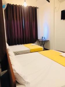 um quarto com 2 camas e uma janela com cortinas em Lotus cool hotel and restaurant em Ibbagomuwa