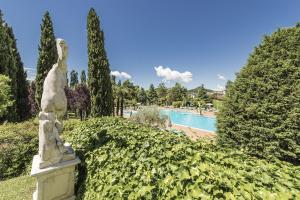 a statue in a garden with a pool in the background at Hotel Des Bains Terme in Montegrotto Terme