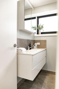 ein weißes Bad mit einem Waschbecken und einem Fenster in der Unterkunft Lottie's - Absolute Convenience in Bicheno