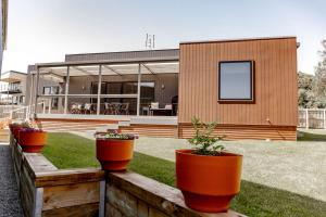 ein Haus mit drei Topfpflanzen auf einem Holzzaun in der Unterkunft Lottie's - Absolute Convenience in Bicheno