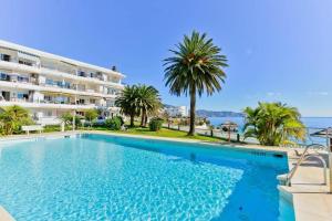 a swimming pool in front of a building with palm trees at Beautiful apartment in Acapulco Playa, Nerja in Nerja