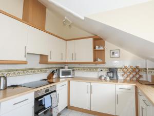 a kitchen with white cabinets and a staircase at Dornberg in Y Felinheli