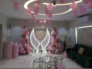 Habitación con globos rosas, mesa y sillas en Challet Orlando park استراحة اورلاندو en Al Mundassah