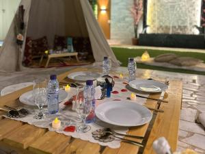 a table with plates and glasses on a table with a tent at Challet Orlando park استراحة اورلاندو in Al Mundassah