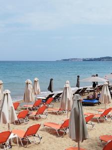 a group of chairs and umbrellas on a beach at Giannis House 2 minutes walk to the beach Peroulia in Kómboi