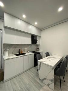 a kitchen with white cabinets and a marble counter top at Apartment in Yerevan in Yerevan