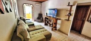 ein Wohnzimmer mit Sofa und Flachbildfernseher in der Unterkunft Casa Sapucaia - Praia in Santa Cruz Cabrália