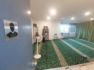 ein Zimmer mit einem grünen Teppich und einem Zimmer mit Stühlen in der Unterkunft Homestay Damai D'Simfoni Kajang- Semenyih in Semenyih
