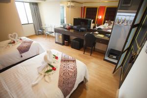 a hotel room with two beds and a desk at Grand Pink Hotel Hatyai in Hat Yai