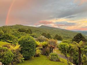 a rainbow in the sky over a garden with trees at The Lake House at Waikaremoana in Tuai