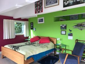 Schlafzimmer mit grünen Wänden und einem Bett mit roten Kissen in der Unterkunft Piringa in Dunedin