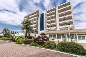 un gran edificio blanco con árboles y arbustos en Hotel Des Bains Terme en Montegrotto Terme