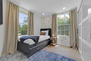 a bedroom with a bed and a large window at Palm Wave Says - 5 min to Best Locations in West Palm Beach