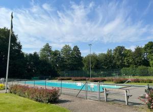 a swimming pool with a bench in a park at A Cozy Retreat Close to Lake in Hjärnarp