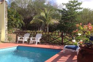 two white chairs sitting next to a swimming pool at Bright & Beautiful 2 Bedroom Villa in Cap Estate