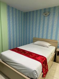 um quarto com uma cama com um cobertor vermelho em Woodlands Inn em Bangkok