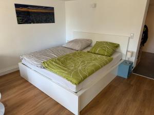 a white bed with a green comforter and pillows at Modernes Apartment, ruhige Lage, stadtnah in Kelkheim