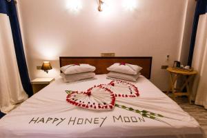 a bed with two pillows and a happy honeymoon sign on it at Hanifaru Beach Inn in Baa Atoll