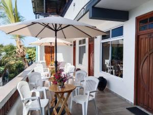 un tavolo con sedie bianche e un ombrellone su un portico di Hanifaru Beach Inn ad Atollo Baa