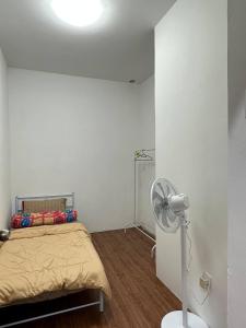 a white room with a bed and a fan at Amir Homestay in Yong Peng