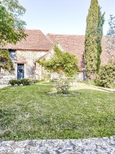 una antigua casa de piedra con un patio de césped en Domaine de pragelier en Tourtoirac