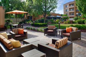 un patio con sillas, mesas y una sombrilla en Courtyard Columbus Worthington, en Worthington