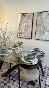 une salle à manger avec une table et des chaises en verre dans l'établissement Stylish modern 2 BR in Lawson, à Belconnen