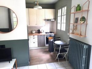 a kitchen with white cabinets and a table and chairs at Magnolia Cottage in Maisons-Laffitte